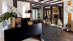 A reception area with a black reception desk, a large wall clock, and a wooden ceiling. - Hotel Boutique Valle de Oca (Valle de Oca)