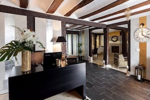 A reception area with a black reception desk, a large wall clock, and a wooden ceiling.