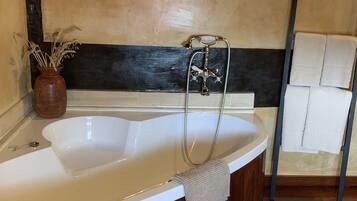 A bathroom with a freestanding bathtub, a towel rack, and a wooden floor.
