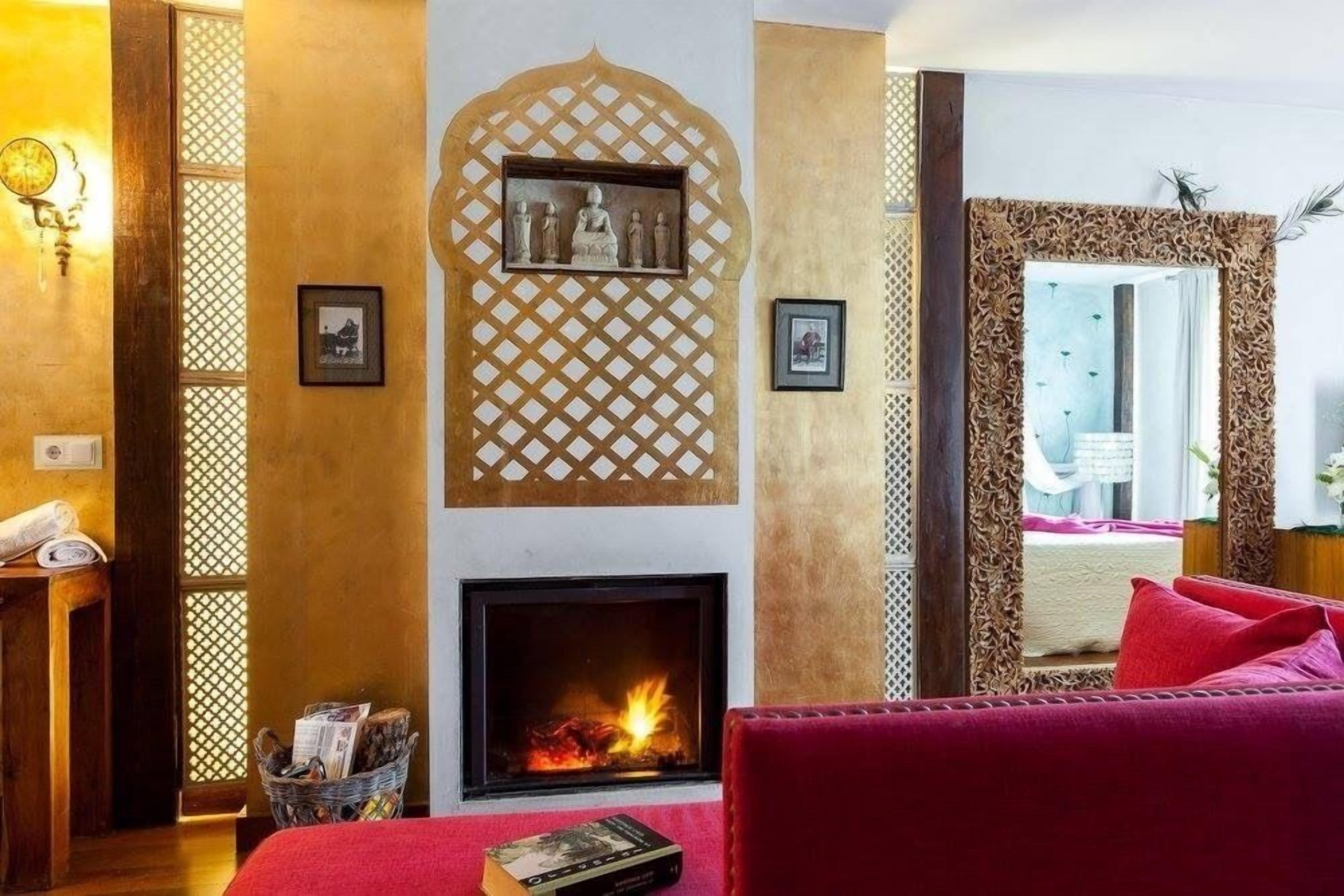 Una habitación con chimenea, un sofá rojo y paneles decorativos en la pared.