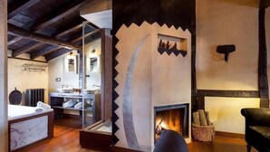 A rustic interior with a fireplace, wooden beams, a glass-enclosed bathroom, and a stone wall with a bull head decoration. - Hotel Boutique Valle de Oca (Valle de Oca)