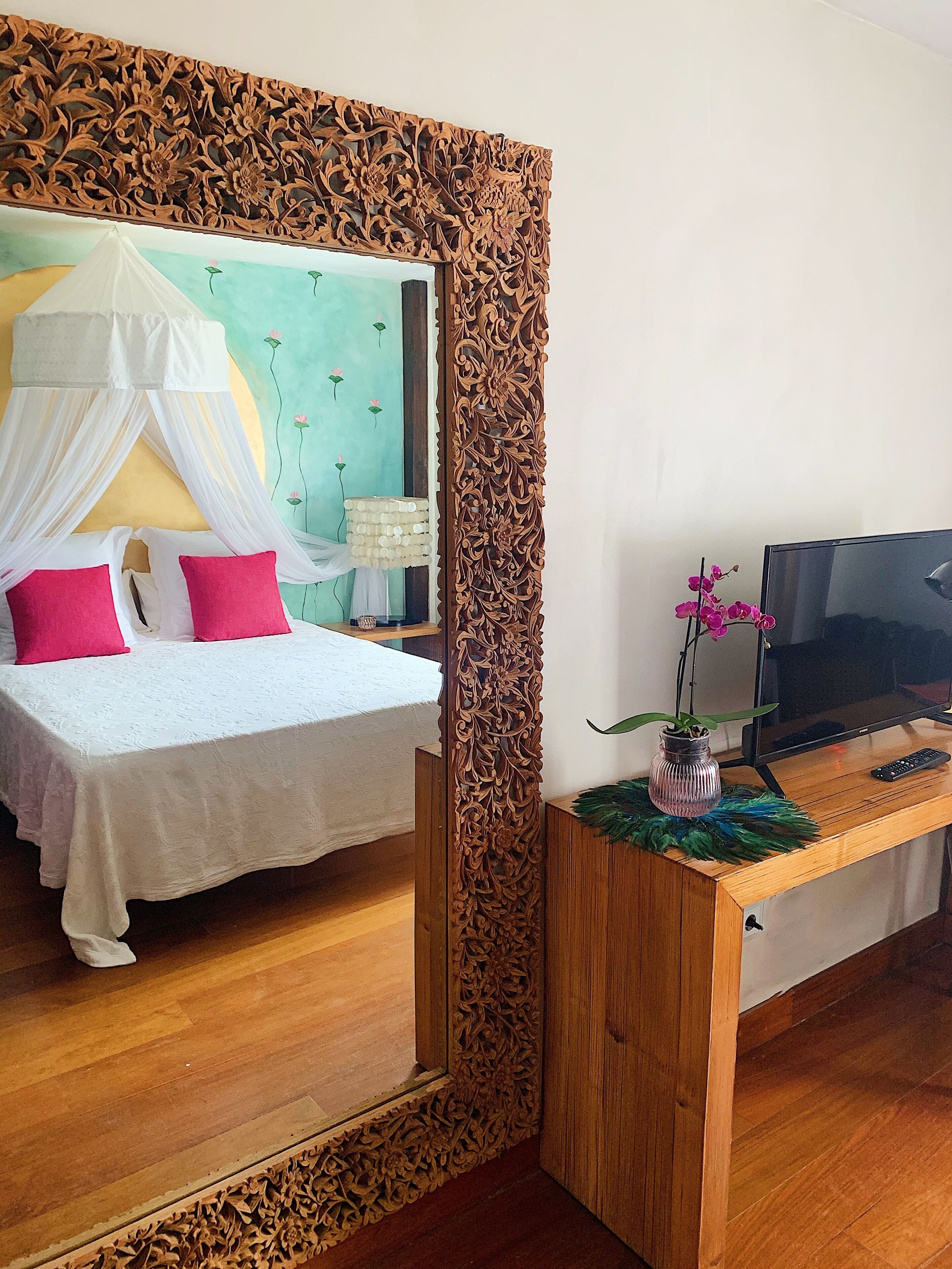 Ein Schlafzimmer mit einem Bett, einem Fernseher und einem Schreibtisch mit einer Vase.