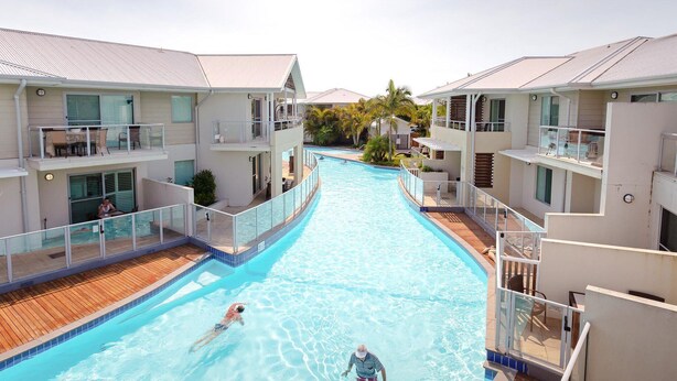 A swimming pool with a wooden deck, surrounded by multi-story buildings with balconies and windows. - Pacific Blue  245-265 Sandy Point Rd - Dual Key Access, air conditioned unit with resort facilities and linen supplied (Salamander Bay)