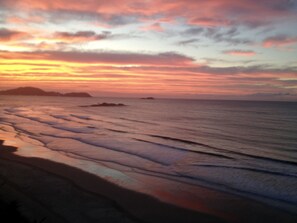 A beach with waves and a sunset.
