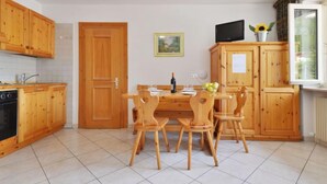 Een keuken met houten kastjes, een eettafel met stoelen, een fornuis en een raam met uitzicht.
