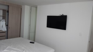 Ein Schlafzimmer mit Bett, Wand-Fernseher, Kleiderschrank und Schrank.