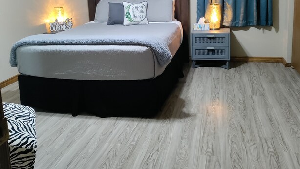 A bedroom with a bed, bedside tables, a wall-mounted light, and a window with curtains.