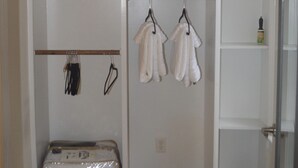 Un armario espacioso con varias estanterías, una barra para colgar ropa y una maleta.