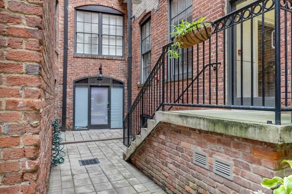 Stroll through this charming alleyway to a historic building with a traditional design, featuring a curved staircase and a large arched window.