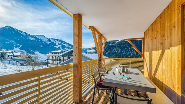 A wooden balcony with a table and chairs, overlooking a snowy mountain landscape. - Flat 6 pers - modern, central, ski in ski out (CHATEL)