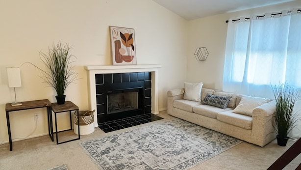 Una sala de estar con chimenea, un sofá, una mesa de centro y dos mesitas auxiliares.