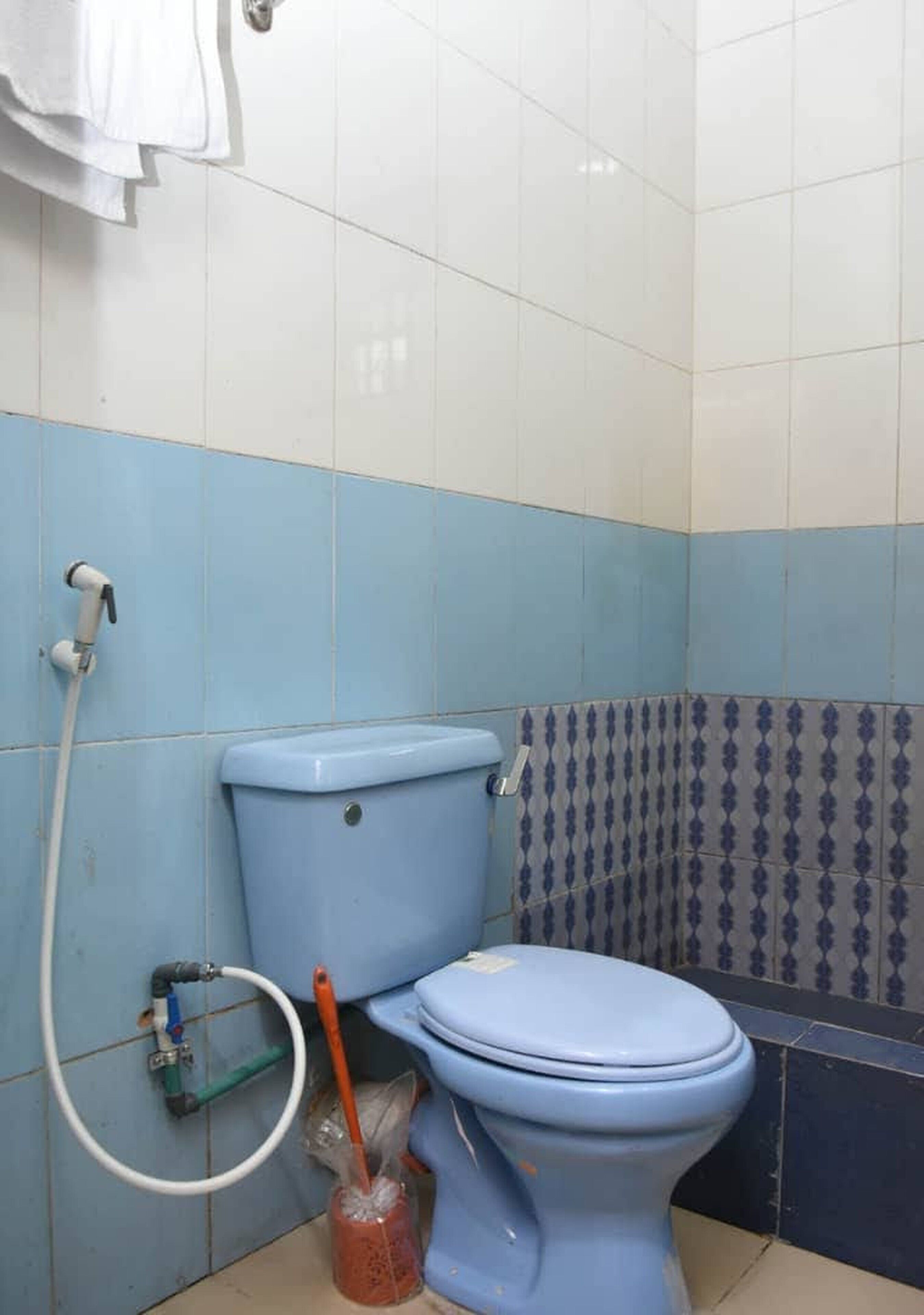 A bathroom with a toilet, a shower, and a tiled wall.