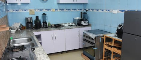 A kitchen with a gas stove, oven, toaster, blender, and coffee maker.
