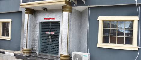 A reception area with a door marked "RECEPTION," a wall-mounted air conditioning unit, and a window with a grid pattern.