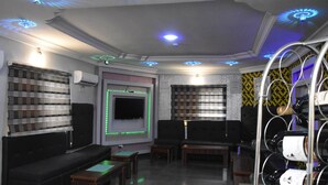 A modern lounge area with a flat-screen TV, comfortable seating, and a wine rack. - PrimeMeridian 24/7 Electricity Hotel & Restaurant (Lekki)