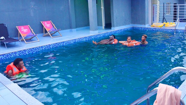A swimming pool with lounge chairs and a lifeguard. - PrimeMeridian 24/7 Electricity Hotel & Restaurant (Lekki)