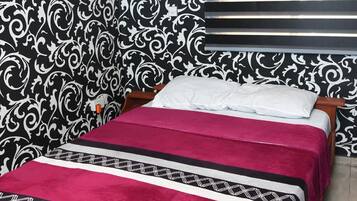 A neatly made bed with a patterned bedspread and a decorative headboard.