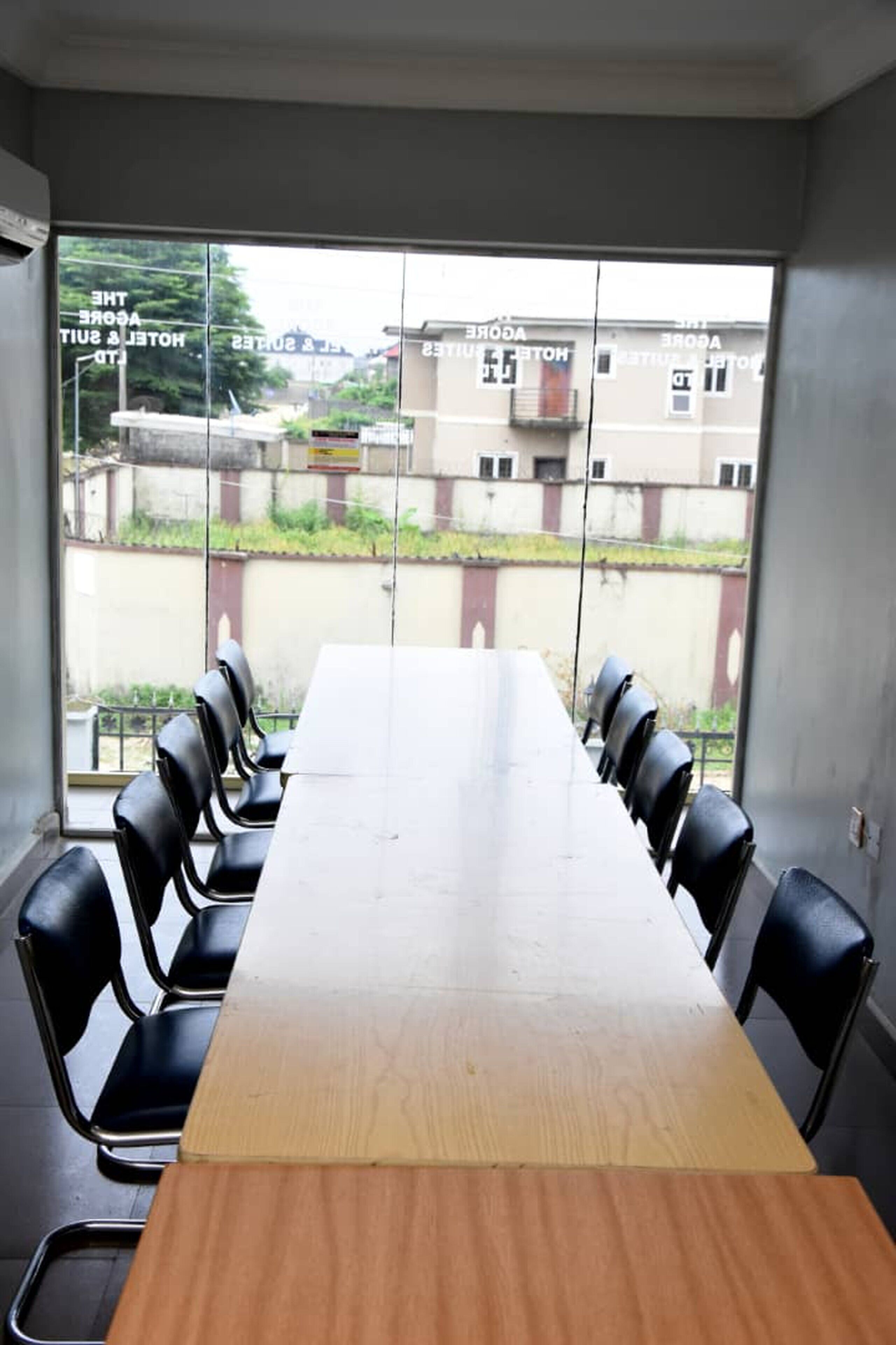 A conference room with a long wooden table and black chairs.