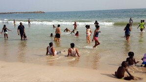A beach with people swimming and walking in the water. - PrimeMeridian 24/7 Electricity Hotel & Restaurant (Lekki)
