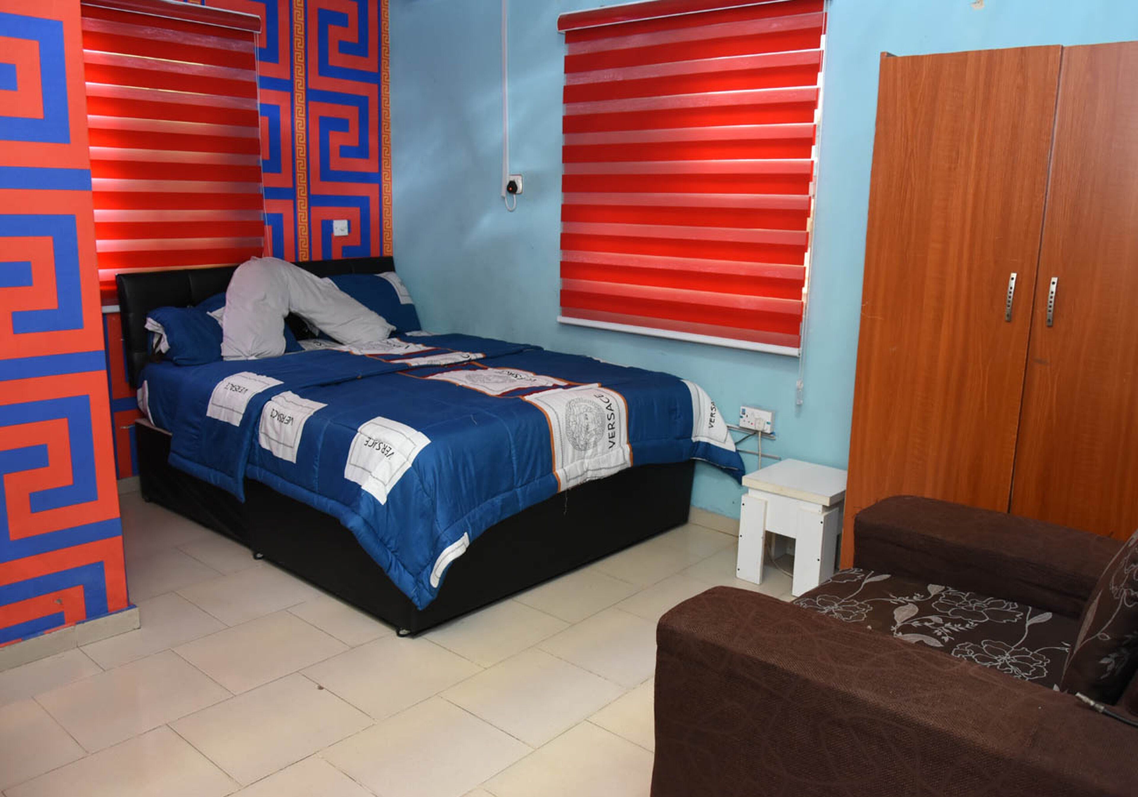 A bedroom with a bed, a small table, a wardrobe, and a sofa.