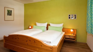 Een slaapkamer met een houten bed, groene wanden en een nachtkastje met een lamp.
