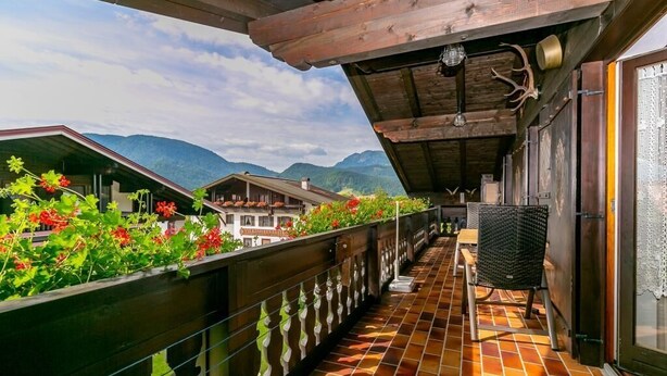 A balcony with a tiled floor, wooden railing, and a view of mountains. - Cozy apartment, 45m², balcony and separate kitchen (Reit im Winkl)