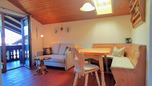 A cozy room with a wooden ceiling, a sofa, a dining table, and a dog. - Cozy apartment, 45m², balcony and separate kitchen (Reit im Winkl)