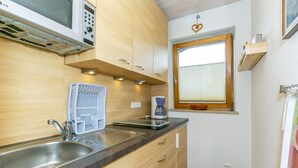 A compact kitchen with a microwave, sink, and coffee maker. - Cozy apartment, 45m², balcony and separate kitchen (Reit im Winkl)