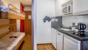 A compact room with a bunk bed, a kitchenette with a microwave, a coffee maker, and a dishwasher. - Rond Point des Pistes (Val Claret) by Interhome (Tignes)