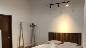 Un dormitorio con cama, cabecera de madera, escalera y lámpara colgante.