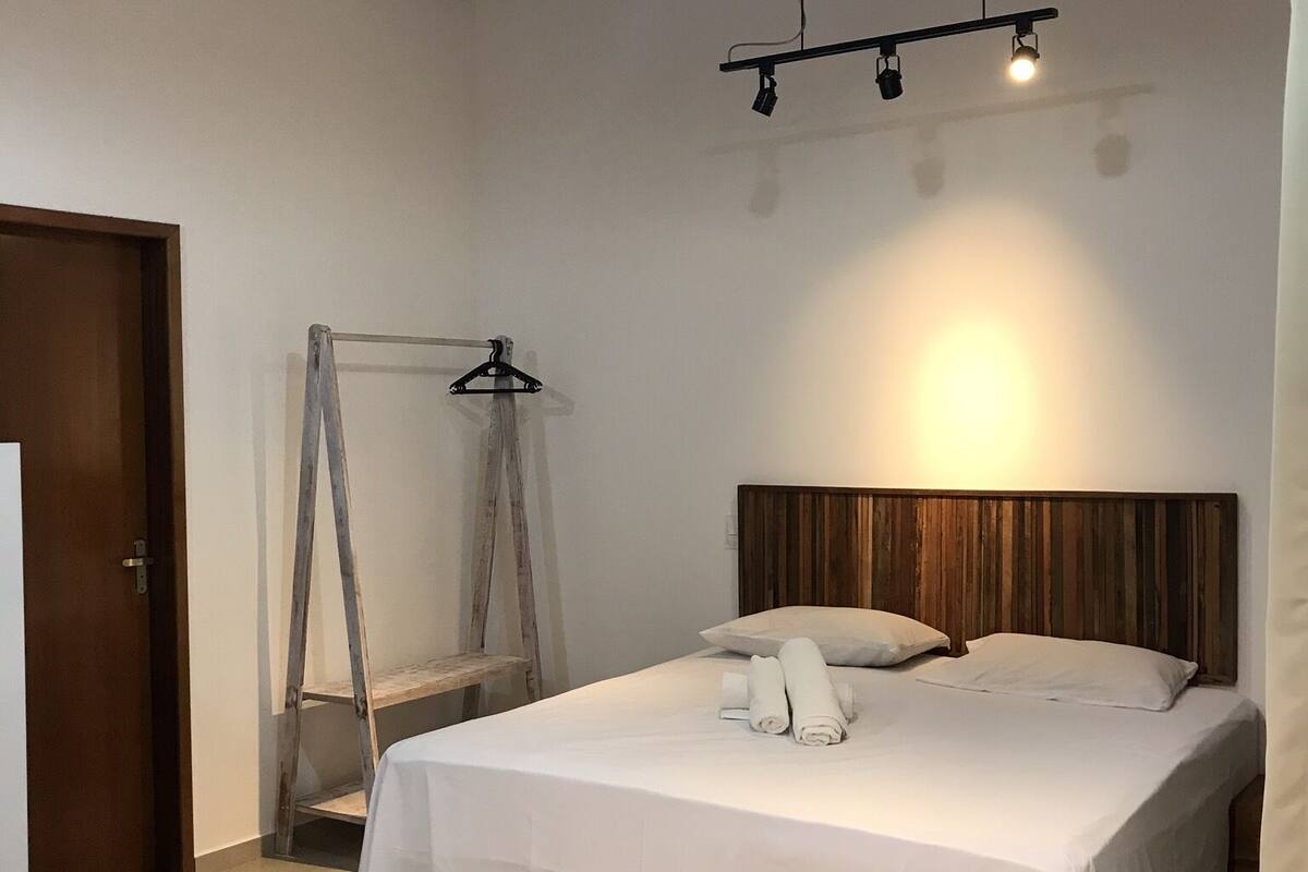 Ein Schlafzimmer mit einem Bett, einem Holz-Kopfteil, einer Leiter und einer Hängeleuchte.