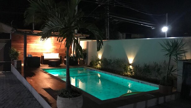 Una piscina con cubierta de madera, un área de descanso con sofá e iluminación empotrada en la pared.