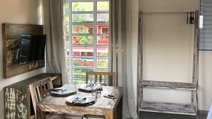 Un comedor con una mesa de madera, sillas y un televisor colgado en la pared.