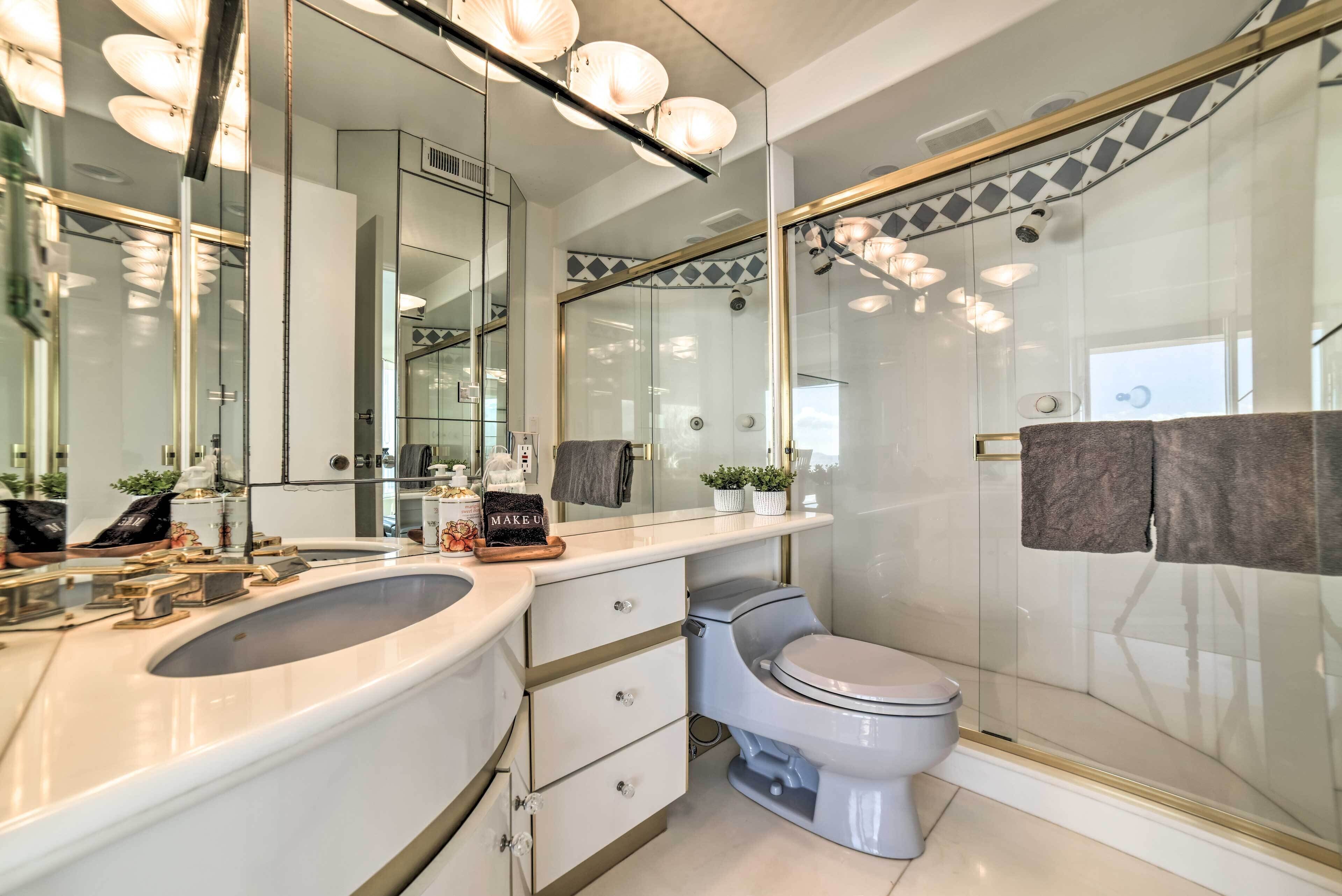 A modern bathroom with a glass-enclosed shower, a white vanity with a sink, and a toilet.
