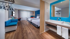 A hotel room with a sofa, two beds, a bathroom with a large mirror, and wooden flooring. - Holiday Inn Express Ningbo City Center by IHG (Ningbo)