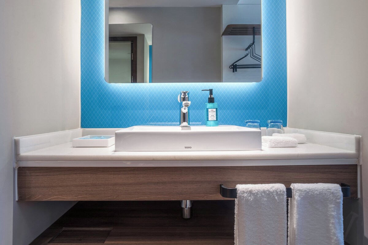 A modern bathroom with a white sink, blue accent wall, and a mirror above it.
