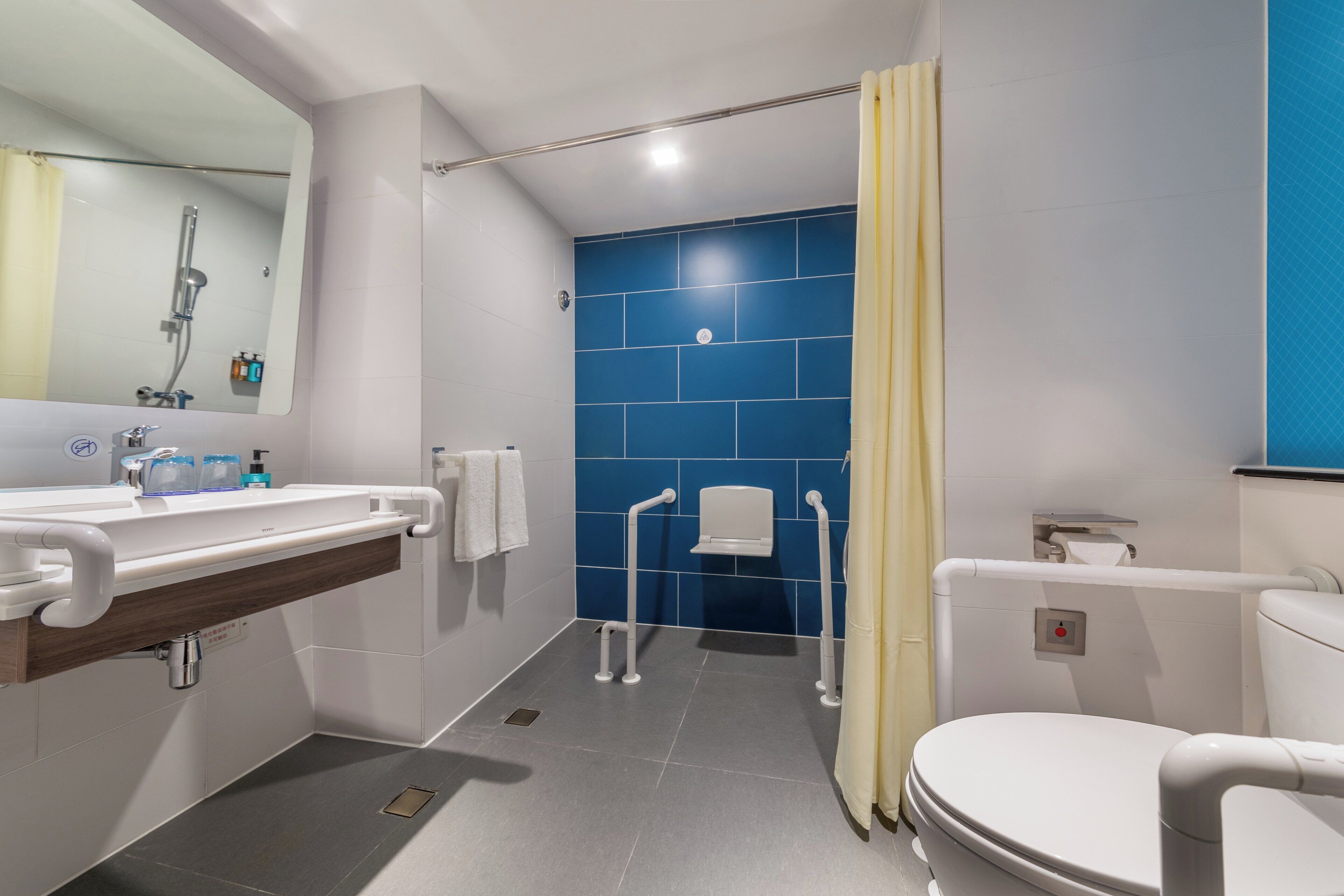 Ein modernes Badezimmer mit Waschbecken, Spiegel, Toilette und blauen Fliesen.