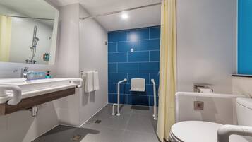 A modern bathroom with a sink, mirror, toilet, and blue tiles.