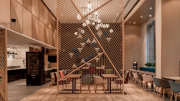 A modern interior with a wooden staircase, a hanging light fixture, and a seating area. - Holiday Inn Express Ningbo City Center by IHG (Ningbo)