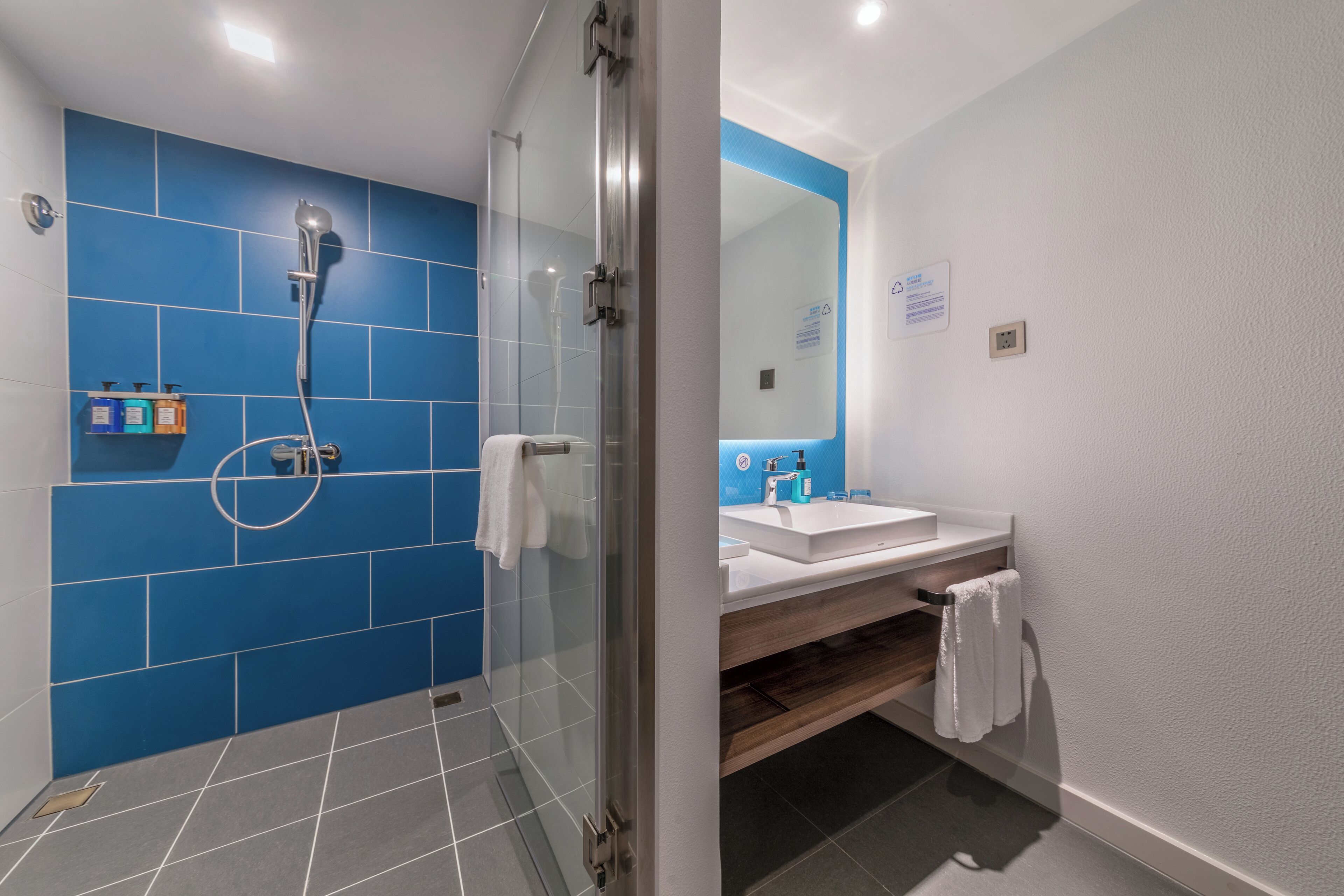 Un baño moderno con cabina de ducha de vidrio, un lavabo blanco y un espejo.