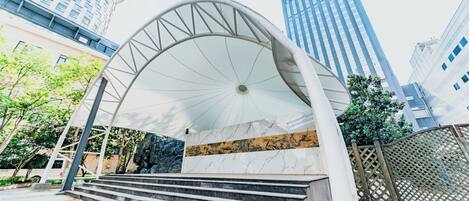 A modern building with a curved glass entrance and marble steps leading up to it.