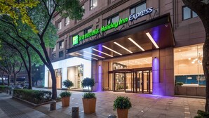 A Holiday Inn Express building with a modern facade, large glass entrance, and potted plants in front. - Holiday Inn Express Ningbo City Center by IHG (Ningbo)