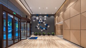 A modern lobby with a geometric wall design, wooden flooring, and a glass entrance. - Holiday Inn Express Ningbo City Center by IHG (Ningbo)