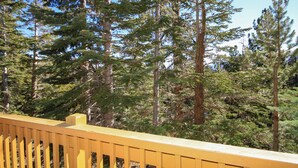 A yellow railing overlooking a forest of tall evergreen trees. - Mammoth Ski & Racquet Club #51 - Pet Friendly (Mammoth Lakes)