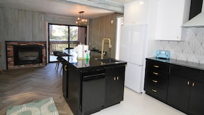 A modern kitchen with black cabinetry, a built-in dishwasher, and a large island. - Mammoth Ski & Racquet Club #51 - Pet Friendly (Mammoth Lakes)