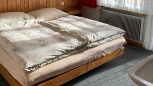 Et værelse med en træseng, en rødlamp, en radiator og et vindue med let gardin.