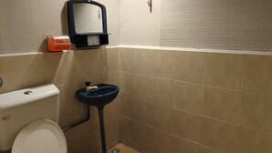 Et badeværelse med toilet, bidet og en blå spand.