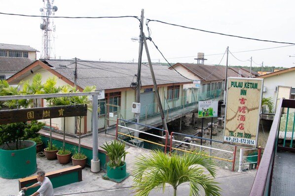 Una posada en Pulau Ketam, con un letrero, un pequeño jardín con plantas en macetas y un hombre sentado en un banco.