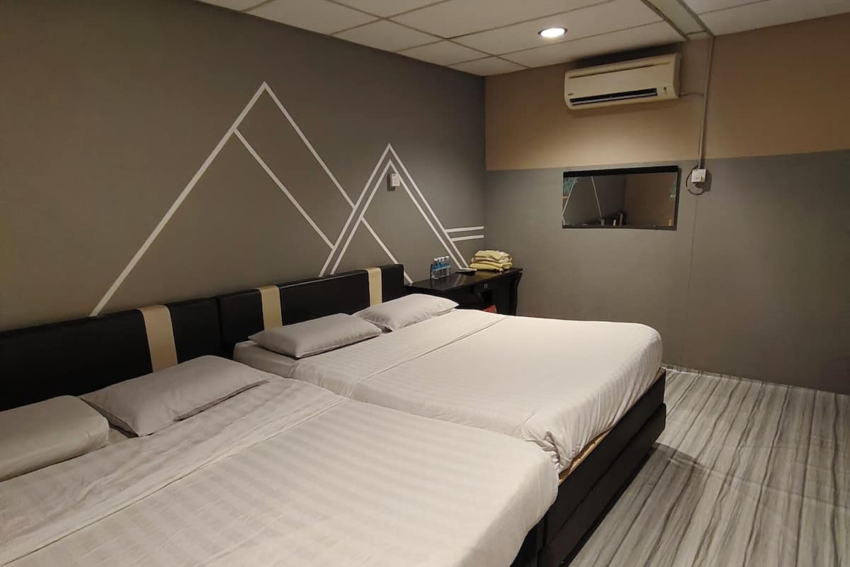 Een hotelkamer met twee bedden, een bureau, een airconditioning en een raam.