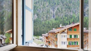 Ein Hotel mit Bergblick, das eine traditionelle Holzfassade und mehrere Balkone bietet.